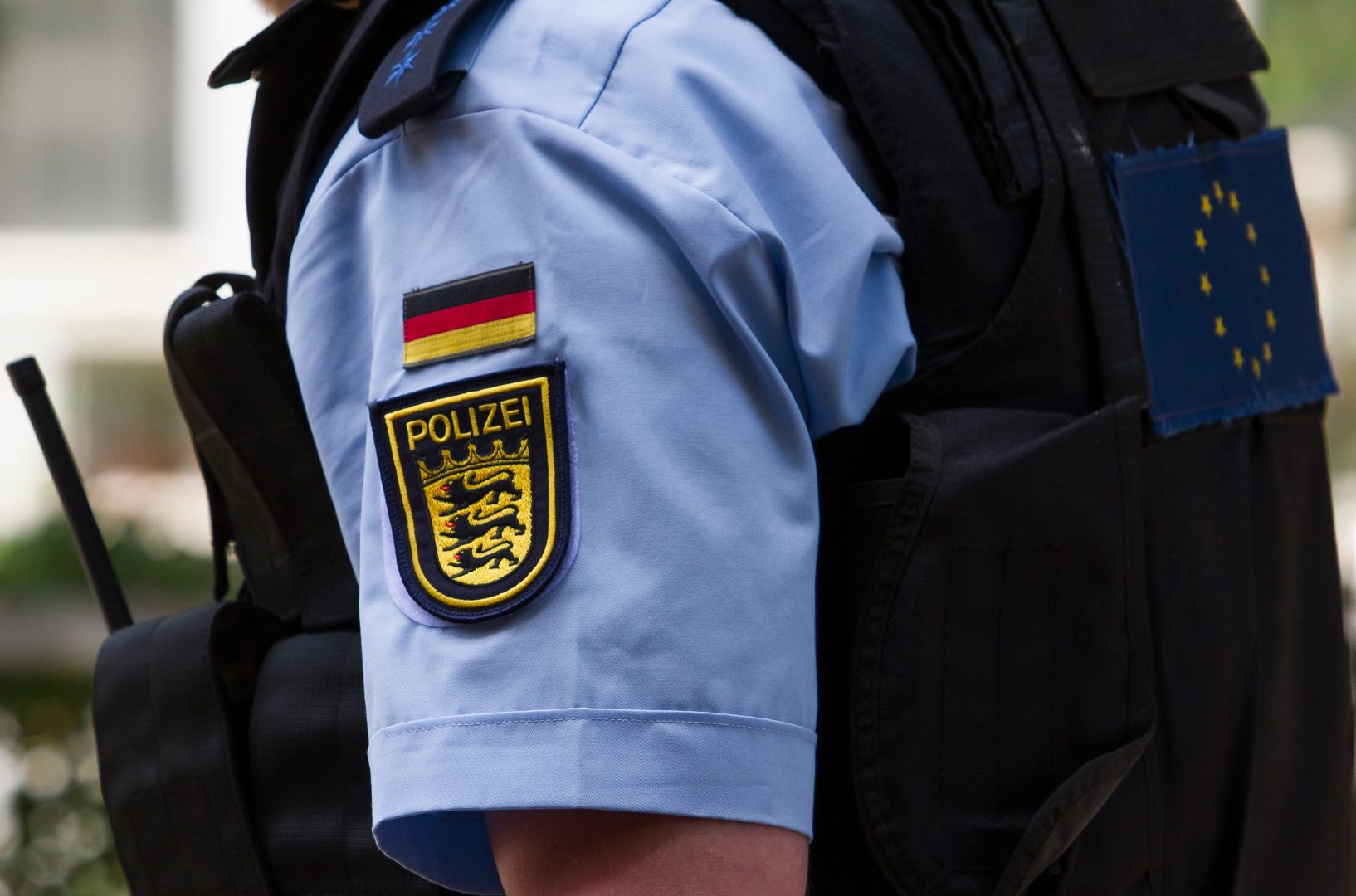 Ein Polizist mit deutschem Polizeiabzeichen und EU-Flagge auf der Uniform.